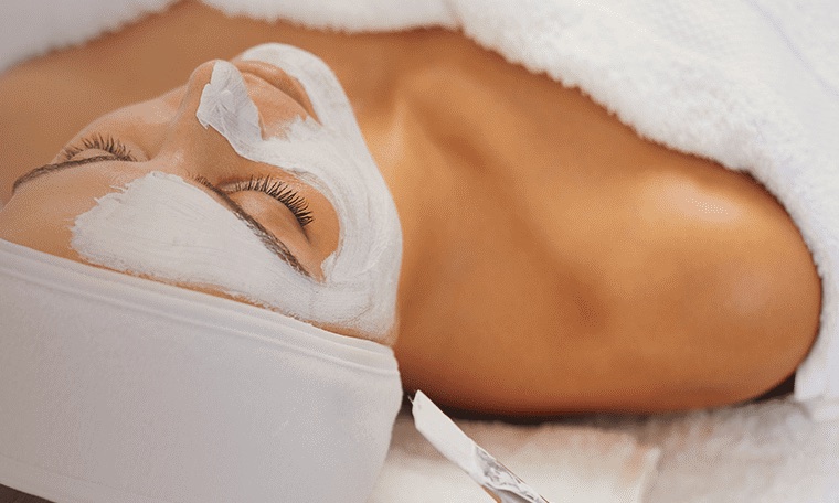 Client relaxing during a facial with a clay mask